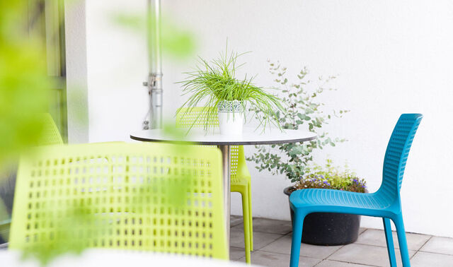 Nahansicht einer Terrasse auf welcher einige Gartenstühle und Tische stehe.  