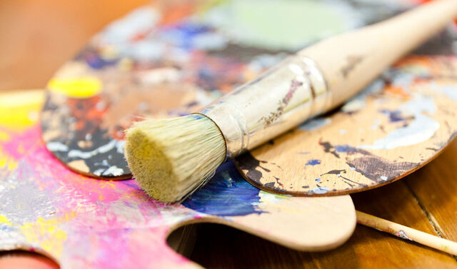 Palette mit Farbkleksen auf dieser liegt ein Pinsel. 